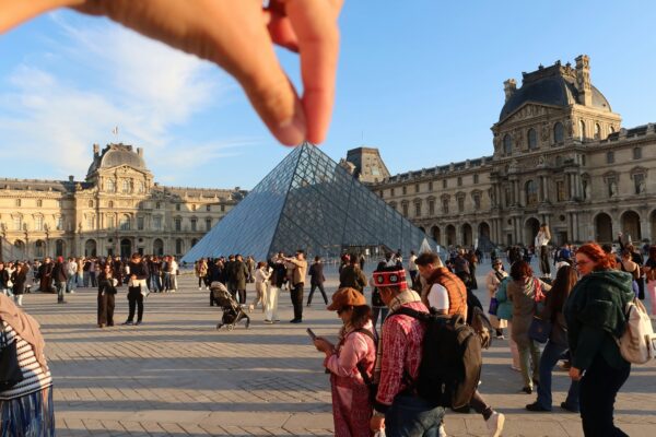 Hand appears to "pinch" the louvre pyramid in paris.