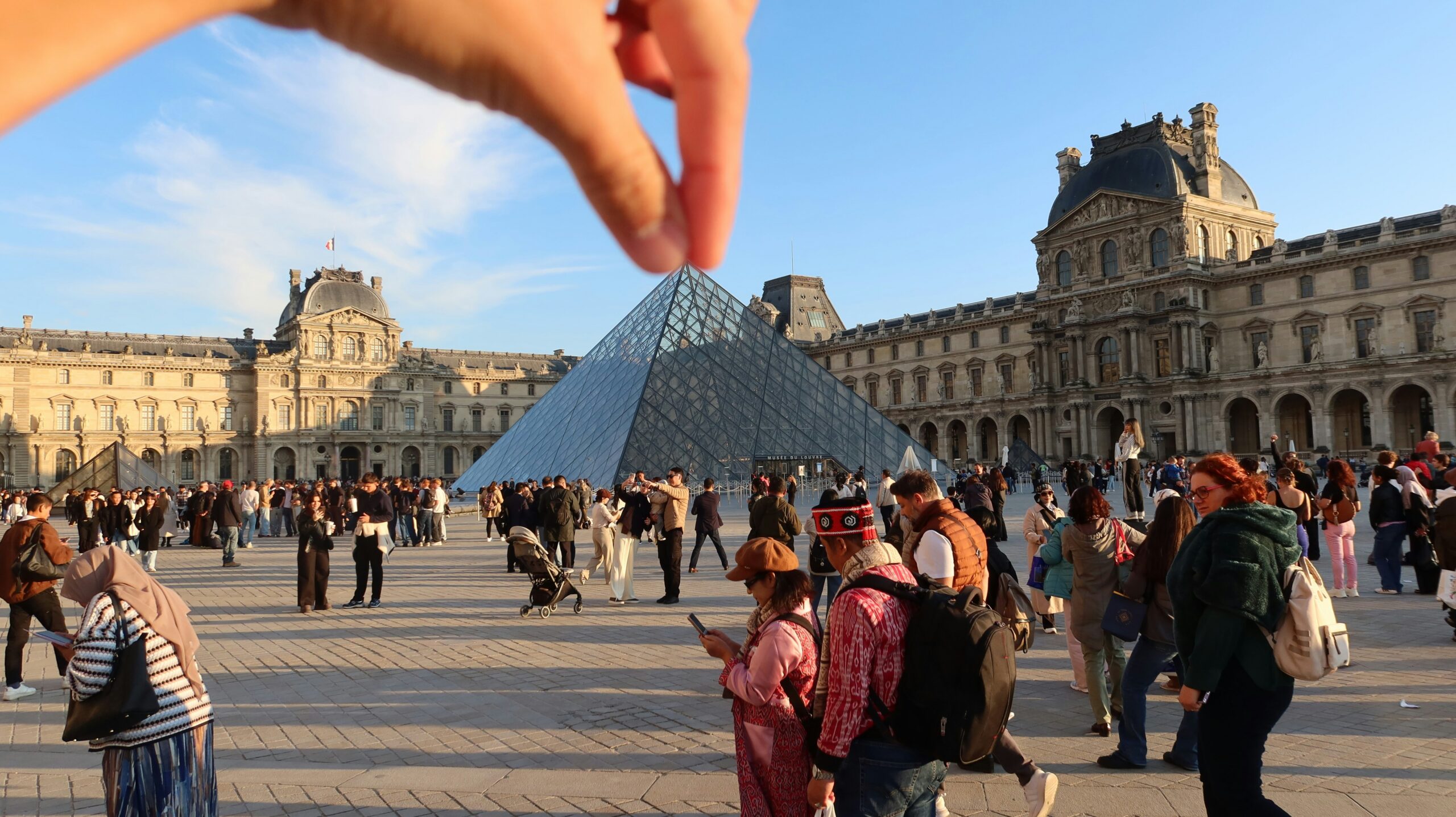 Hand appears to "pinch" the louvre pyramid in paris.