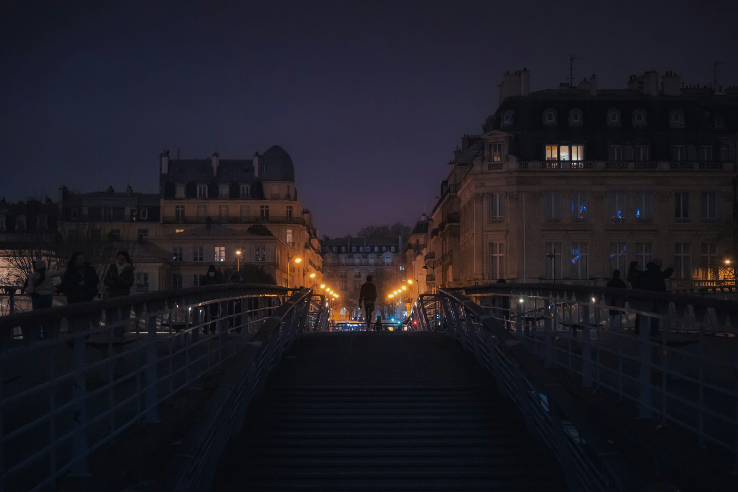 A night scene of a city street with stairs leading up to a building