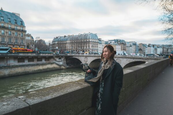 A woman standing on a bridge next to a river