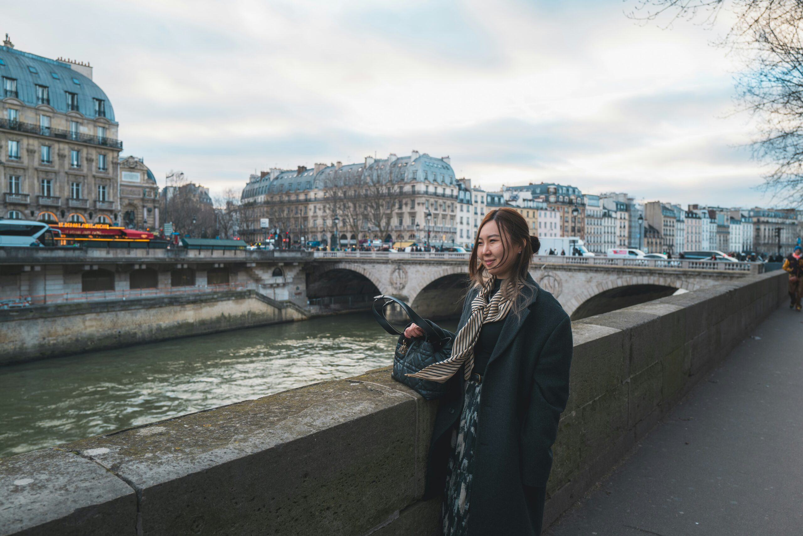 A woman standing on a bridge next to a river