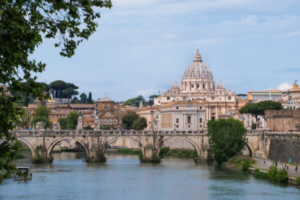 a bridge over a river leading to a large building with a dome on top